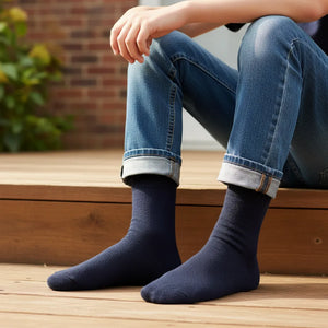 Person wearing navy boot socks and rolled-up jeans sitting on a wooden bench.